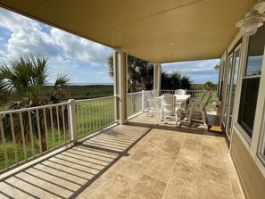 Une terrasse couverte avec une table et des chaises, une vue sur le paysage et une rambarde.