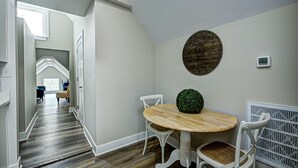 A hallway with a wooden floor, white walls, and a round table with chairs. A decorative round sign is on the wall. - Stylish Condo Close To Everything!  (Indianapolis)