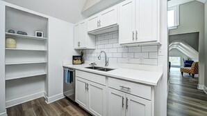 A modern kitchen with white cabinetry, a double sink, and a tiled backsplash. - Stylish Condo Close To Everything!  (Indianapolis)