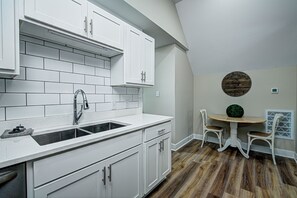 A kitchen with white cabinets, a sink, and a dining area with a round table and chairs.