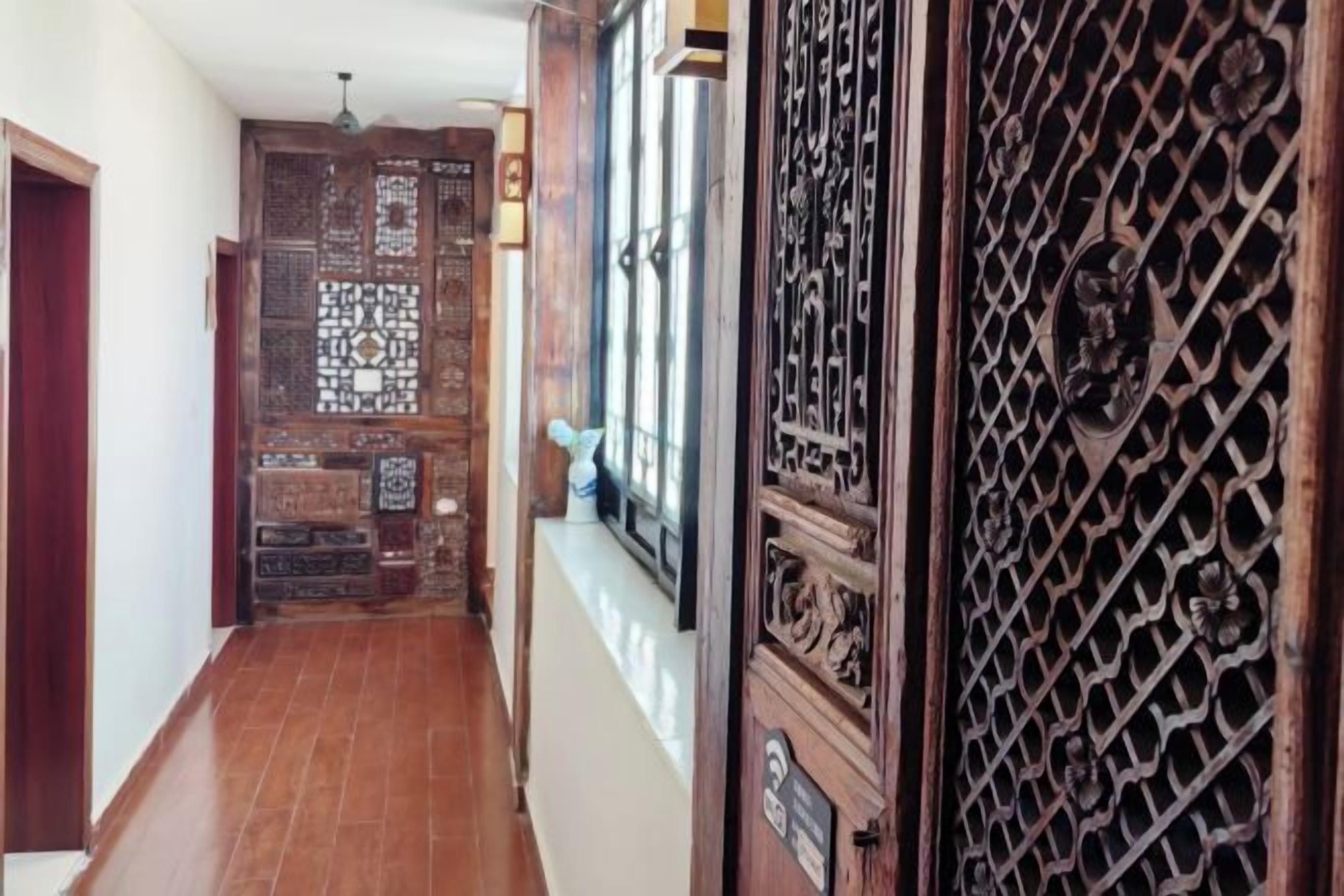 Un pasillo con puerta y ventana de madera, que conduce a una habitación con pared estampada.