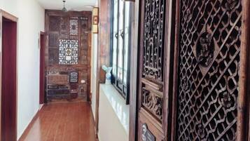Un pasillo con puerta y ventana de madera, que conduce a una habitación con pared estampada.