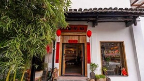 A traditional building with a tiled roof, a wooden door, and red lanterns. - Jingdezhen Guiran Inn (Jingdezhen)