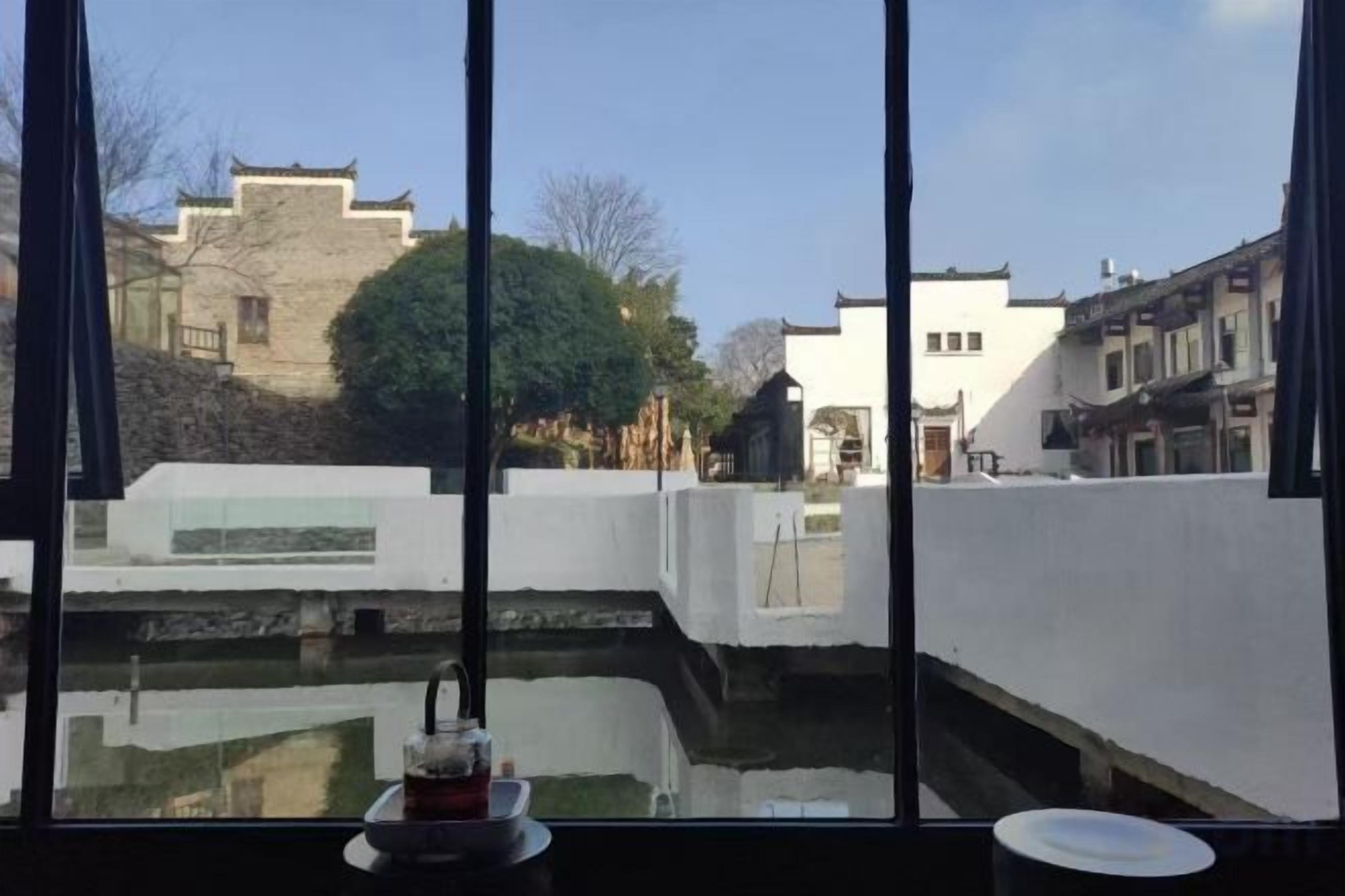 A view through a window with a white wall and a small water feature in the foreground.
