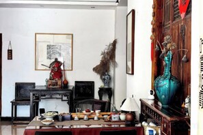 A traditional room with a dining table set, a statue, and a large vase. - Jingdezhen Guiran Inn (Jingdezhen)