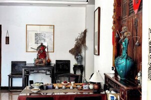 A traditional room with a dining table set, a statue, and a large vase.