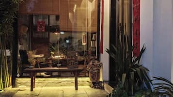 Un espacio de estar al aire libre con una mesa y sillas de madera, rodeado de plantas en macetas.