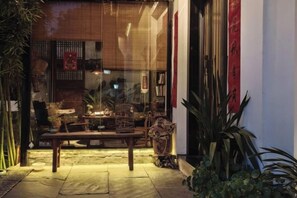 An outdoor seating area with a wooden table and chairs, surrounded by potted plants. - Jingdezhen Guiran Inn (Jingdezhen)