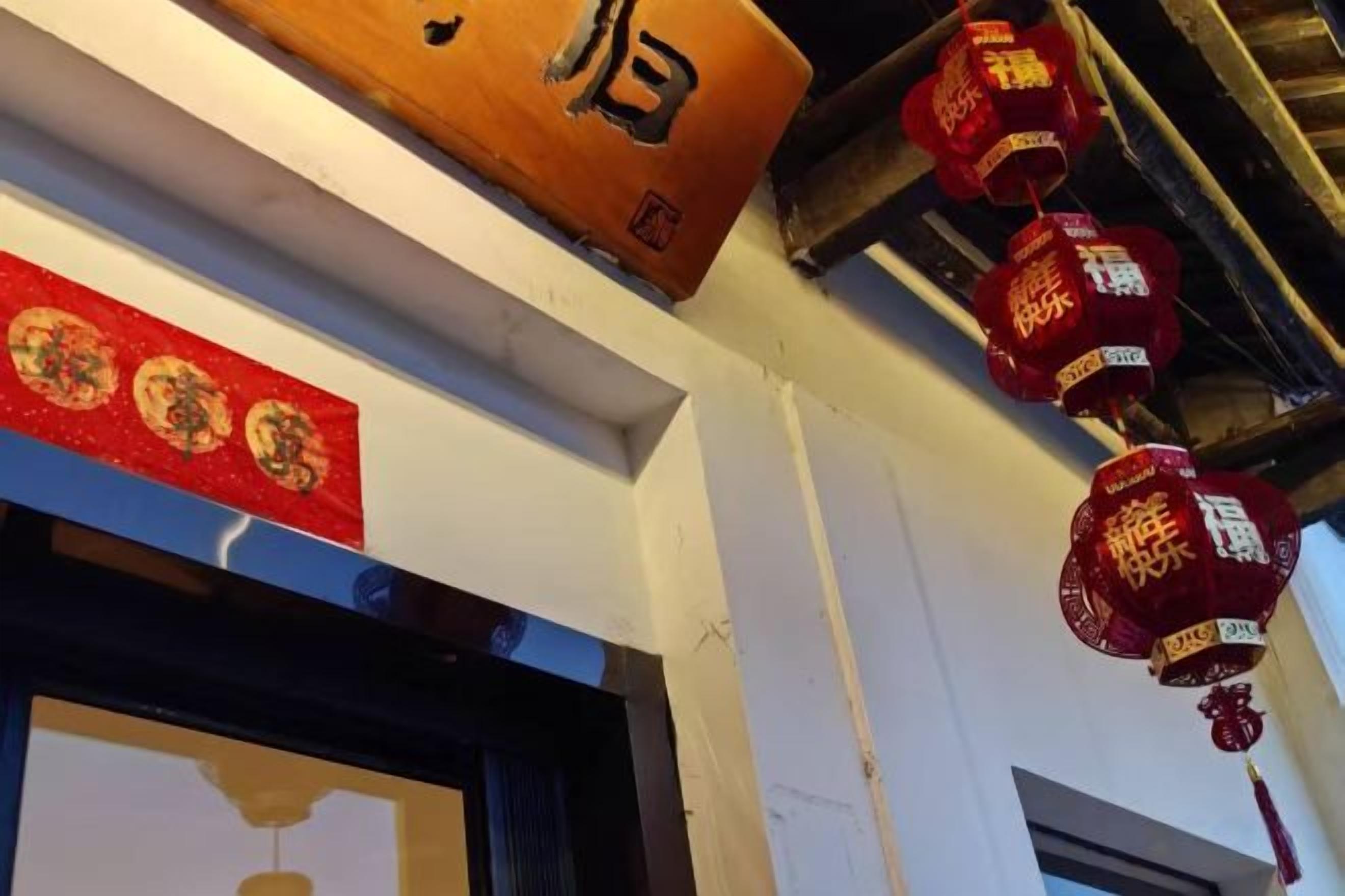 Een gevel met een houten bord en rode lantaarns.