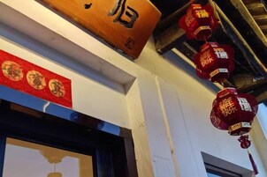 A building facade with a wooden sign and red lanterns.