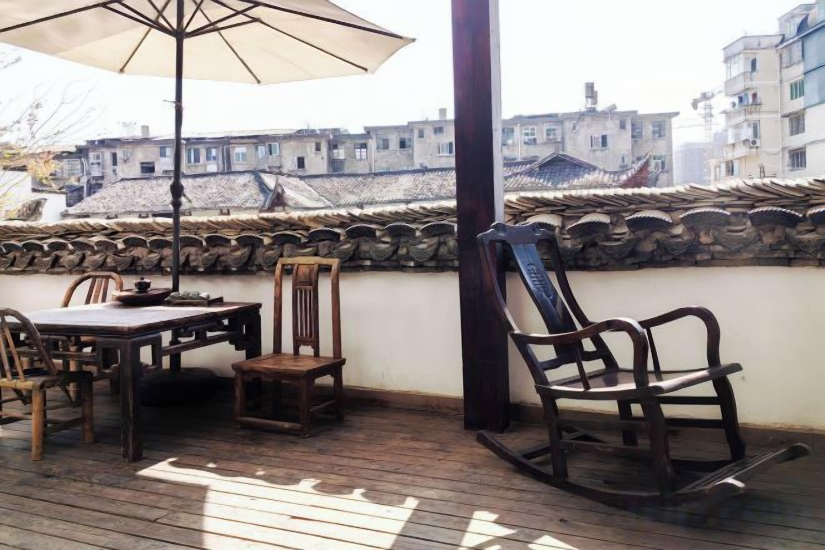 A wooden deck with a table and chairs, a rocking chair, and a large umbrella.