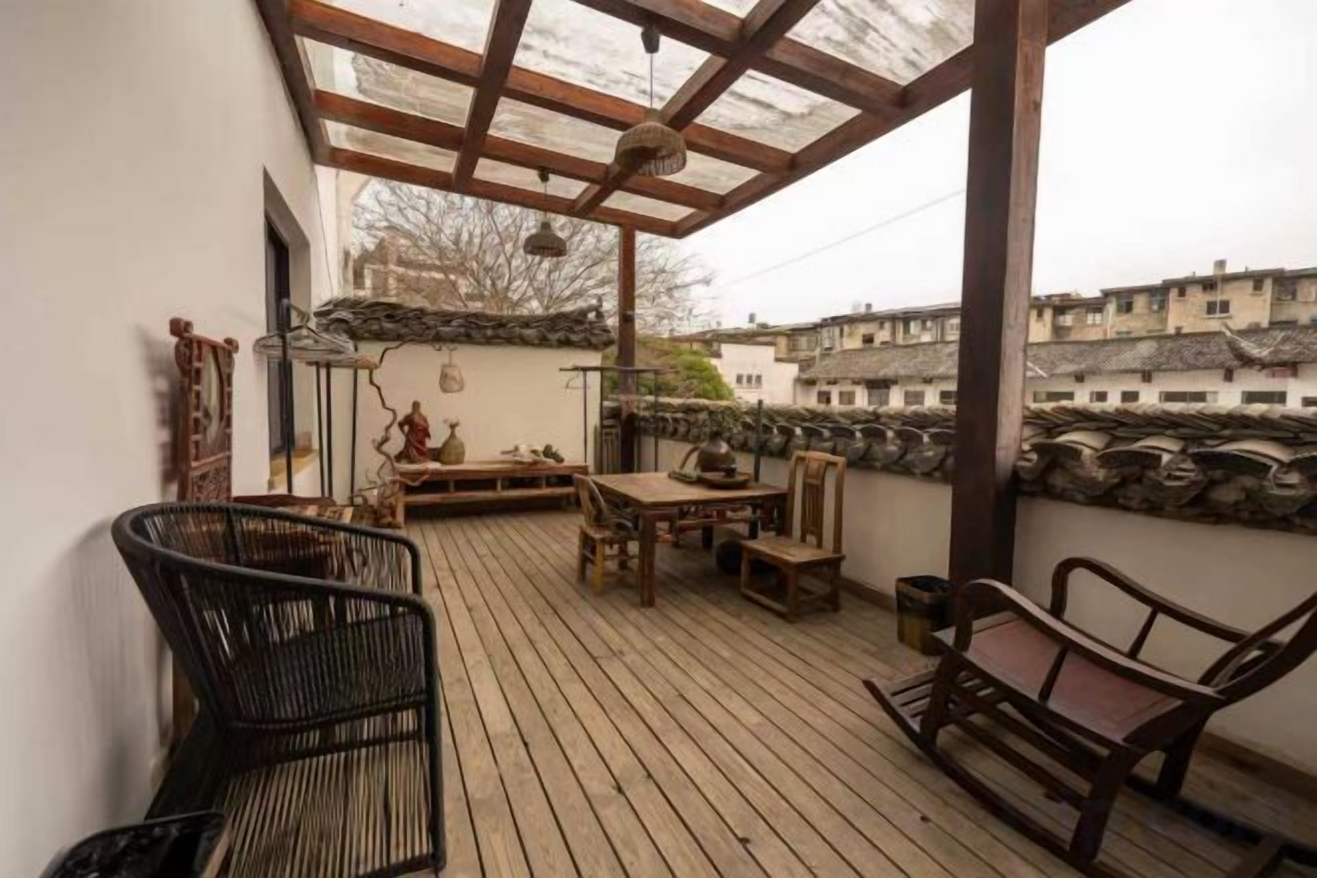 Eine Holzterrasse mit Gartenmöbeln, einer Pergola und einer Steinmauer.