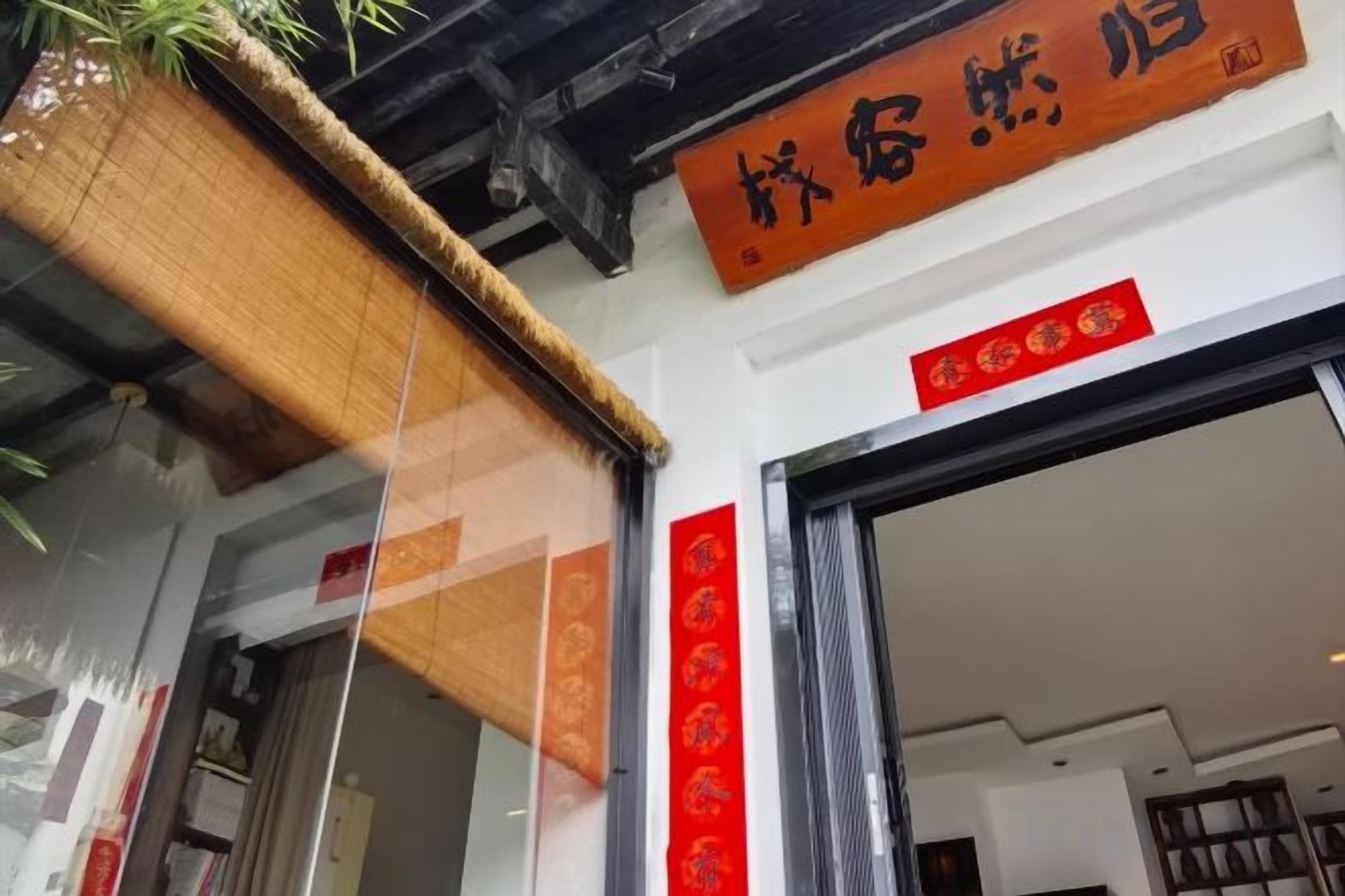 A building entrance with a sign above the door and a red decoration on the wall.