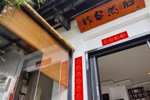 A building entrance with a sign above the door and a red decoration on the wall. - Jingdezhen Guiran Inn (Jingdezhen)