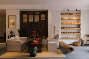 A living room with a sofa, armchairs, a coffee table, and a bookshelf. - Jingdezhen Guiran Inn (Jingdezhen)