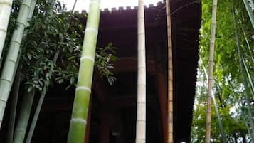 A traditional bamboo structure with a roof, surrounded by tall bamboo trees.