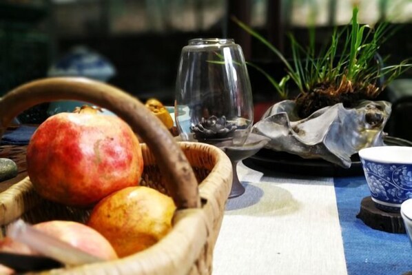A table with a basket containing fruits, a glass, and a decorative item.