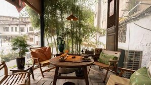 A wooden table with chairs and cushions on a tiled patio. - Jingdezhen Guiran Inn (Jingdezhen)