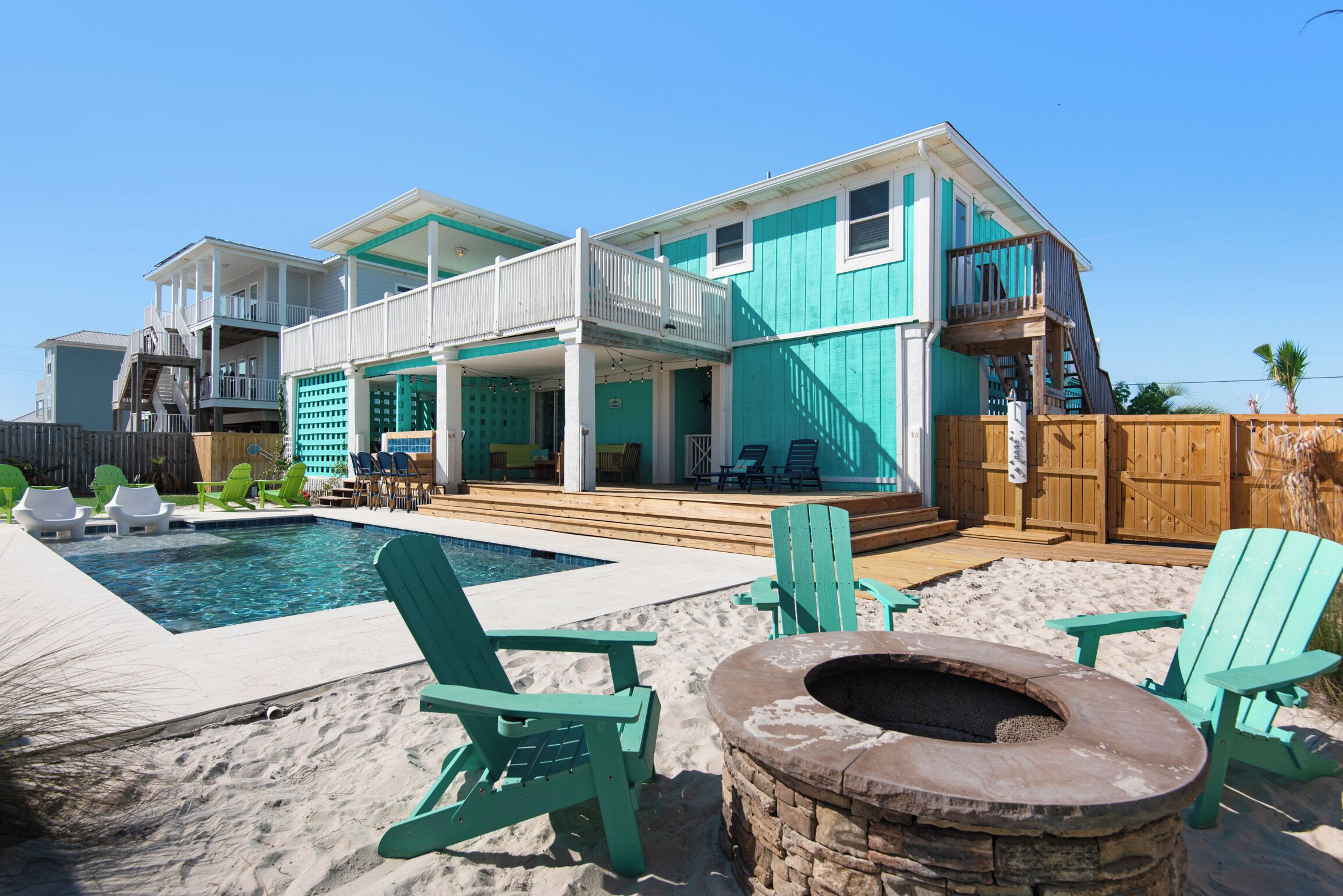 A two-story house with a swimming pool, outdoor seating, and a fire pit.
