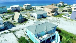 Ett bostadsområde vid kusten med hus, en strand och en fri utsikt över havet.