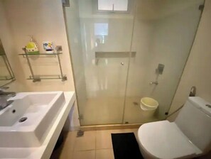 A bathroom with a glass-enclosed shower, a white sink, and a toilet.
