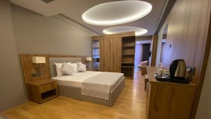 A modern hotel room with a large bed, wooden furniture, and built-in shelving. - KARTAL PARK OTEL (Sirnak)