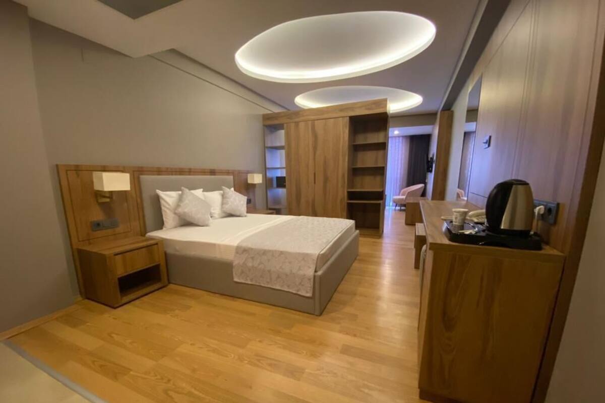 Una habitación de hotel moderna con una cama grande, muebles de madera y estanterías empotradas.