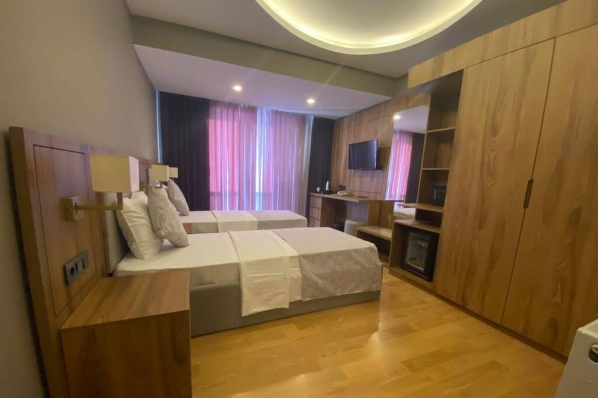 Un dormitorio moderno con dos camas, muebles de madera, un televisor y un armario empotrado.