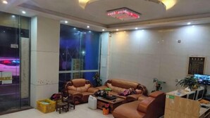 A lobby with leather sofas, a coffee table, and a TV on a desk. - Yingjia Hotel (Zhongshan)