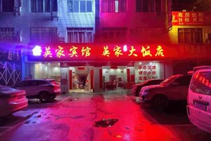 Un edificio con un letrero de neón que indica un hotel y un restaurante. Hay coches estacionados en la calle.