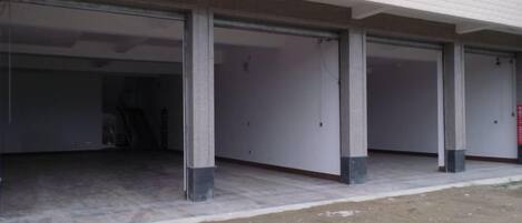 Um edifício com várias entradas tipo garagem, pilares de concreto e terreno de terra.
