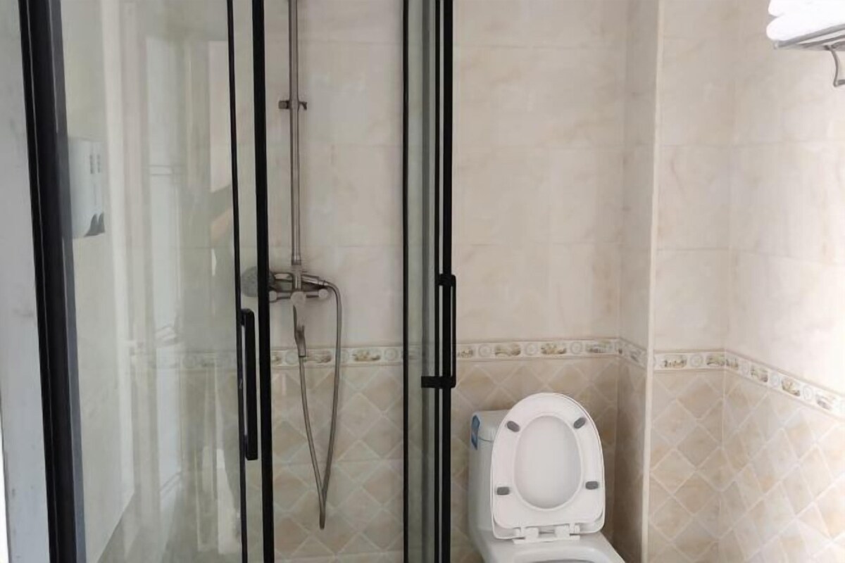 Un baño con ducha envuelta en cristal, inodoro y paredes de azulejos.
