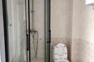 Un baño con ducha envuelta en cristal, inodoro y paredes de azulejos.