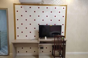A room with a desk, a chair, a television, and a patterned wall.
