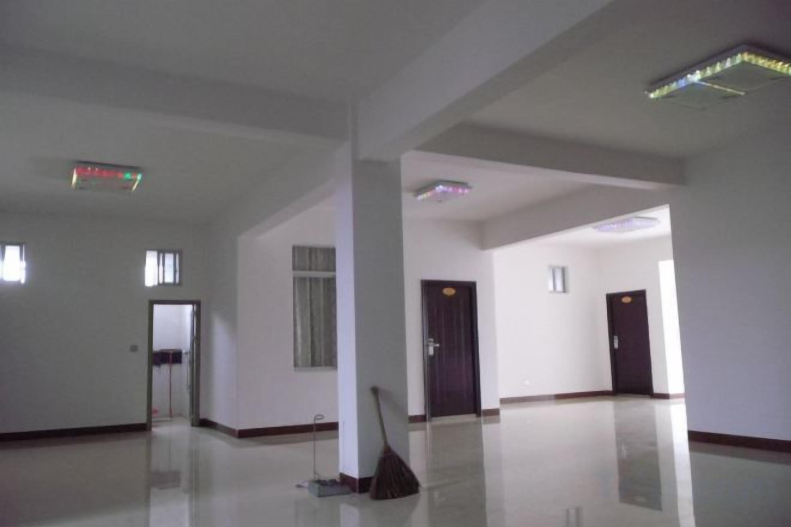 A spacious, empty hotel room with a large mirror, a broom, and a door leading to another room.