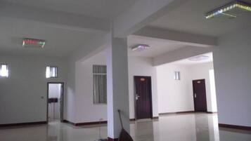 A spacious, empty hotel room with a large mirror, a broom, and a door leading to another room.