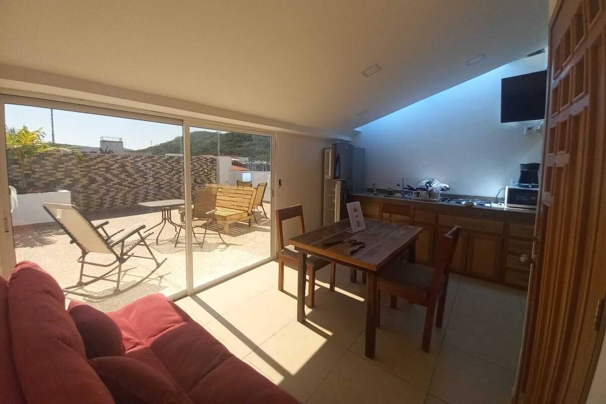 Um apartamento moderno com área de jantar, cozinha e porta de vidro deslizante para um pátio com mobiliário de exterior.