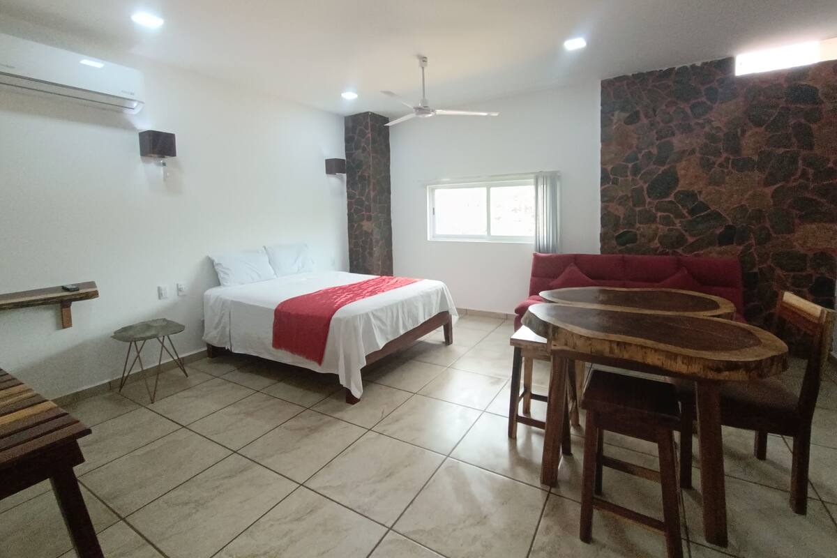 Um quarto com uma cama, uma mesinha, um sofá e uma parede de pedra.
