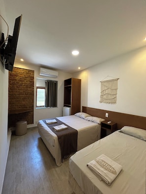 A hotel room with two beds, a stone wall, an air conditioner, a TV mounted on the wall, and a macrame wall hanging. - Suites497 (Rio de Janeiro)