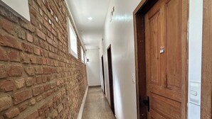A corridor with a brick wall on one side and a wooden door on the other.