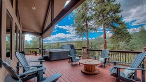 En overdækket terrasse med Adirondack-stole, et rundt træbord og en jacuzzi.