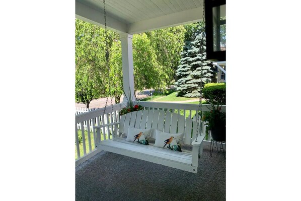 Relax on the covered porch with a comfortable bench and enjoy the serene surroundings.