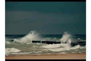 Waves crash against the sea defense structure.