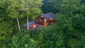 Una cabaña rodeada de un bosque frondoso, con una terraza y zona de estar al aire libre.