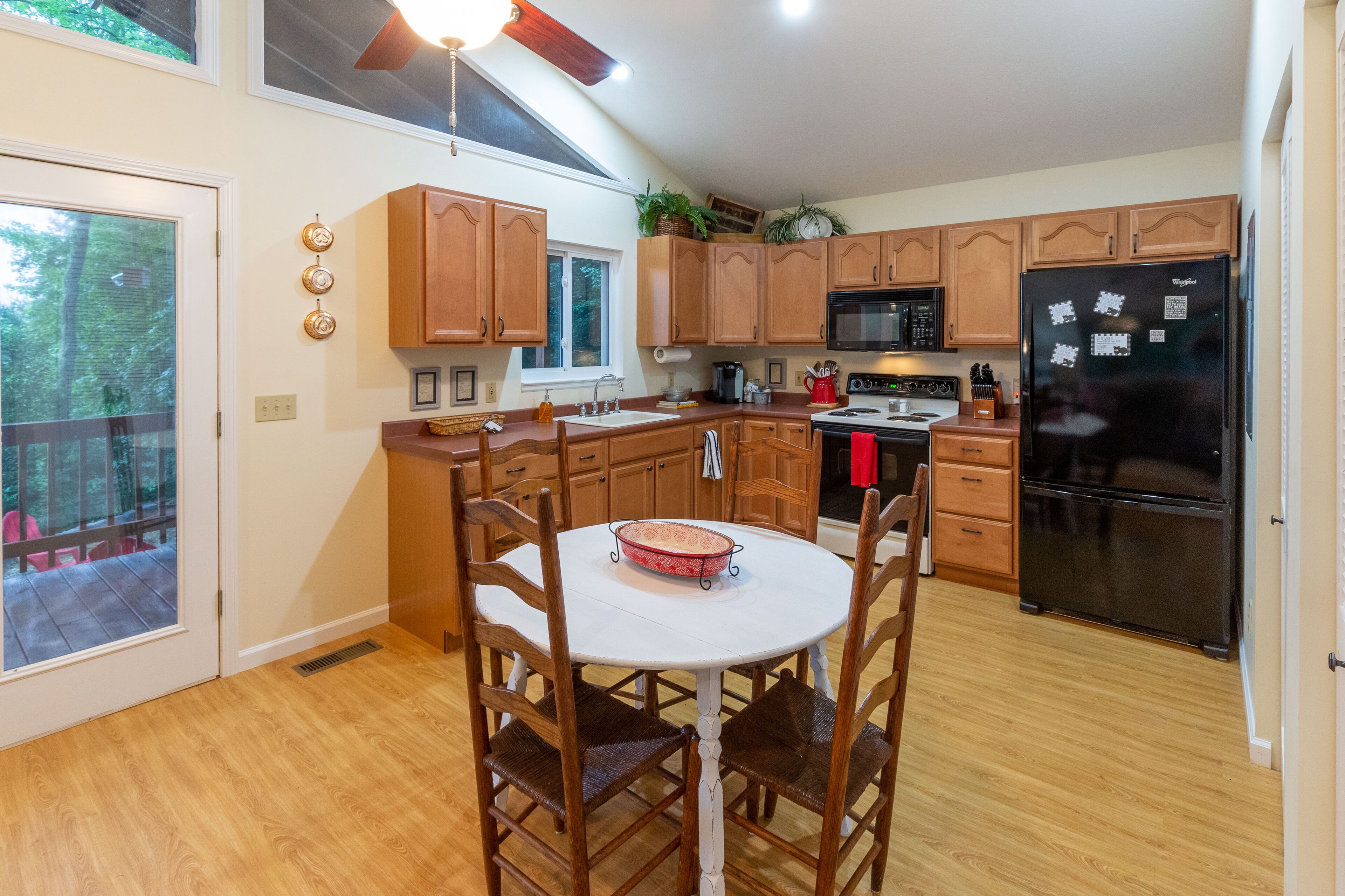 A kitchen with wooden cabinets, a black refrigerator, and a dining table with chairs.