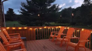 Een houten terras met stoelen en sfeerverlichting.