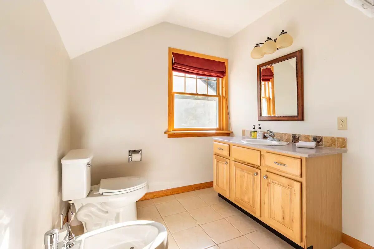 A bathroom with a toilet, sink, and wooden cabinets.