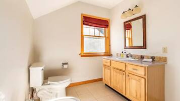 A bathroom with a toilet, sink, and wooden cabinets.