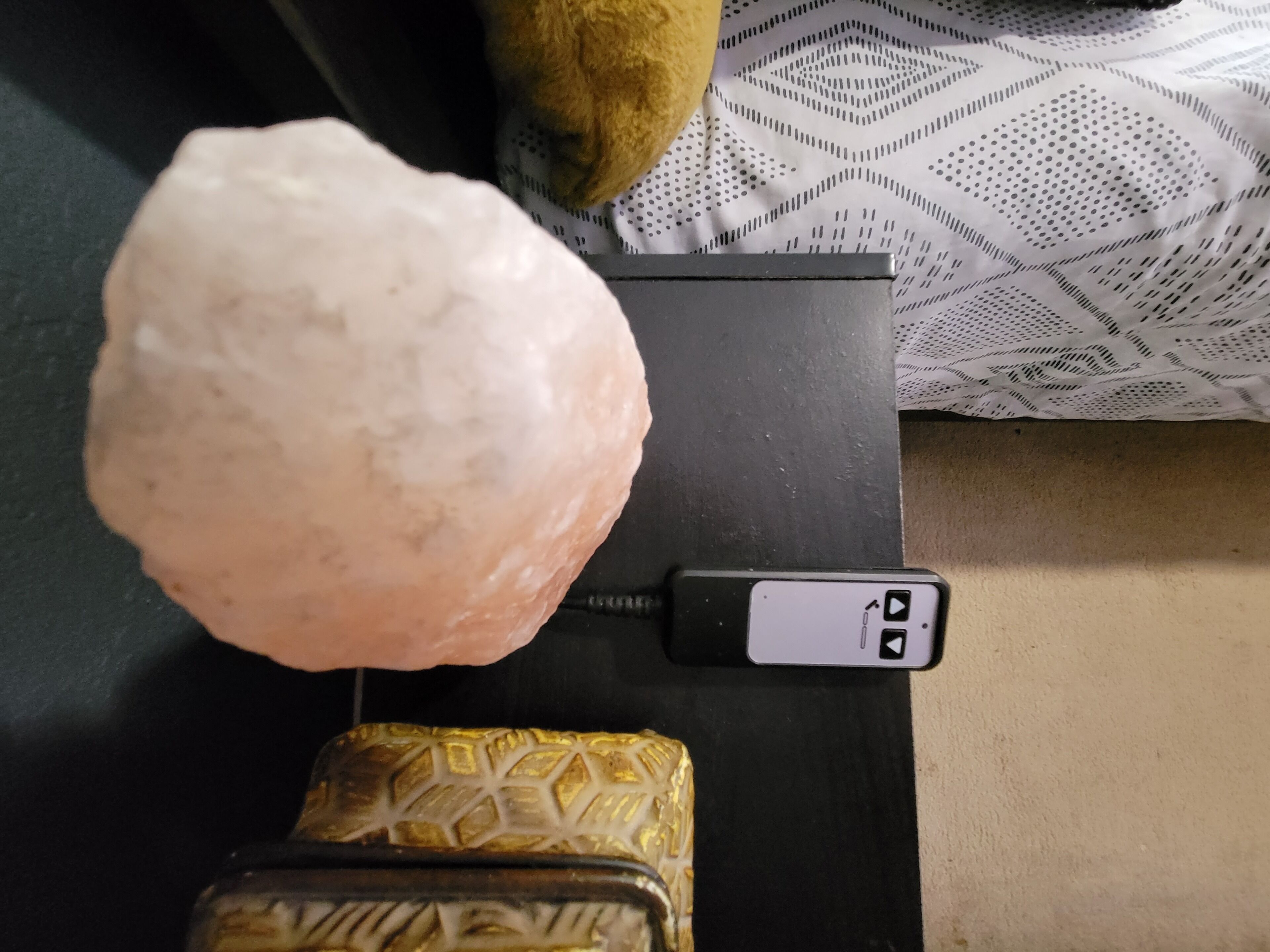 A salt lamp, a decorative item, and a small, patterned object on a black surface.