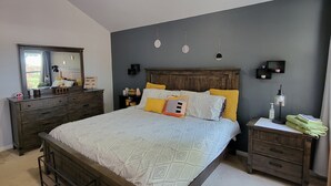 Une chambre à coucher comprenant un lit, des tables de chevet, une commode, un ventilateur de plafond et un miroir.